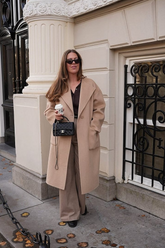a lady in a brown shirt, a pair of brown wide leg pants and a light brown wool coat